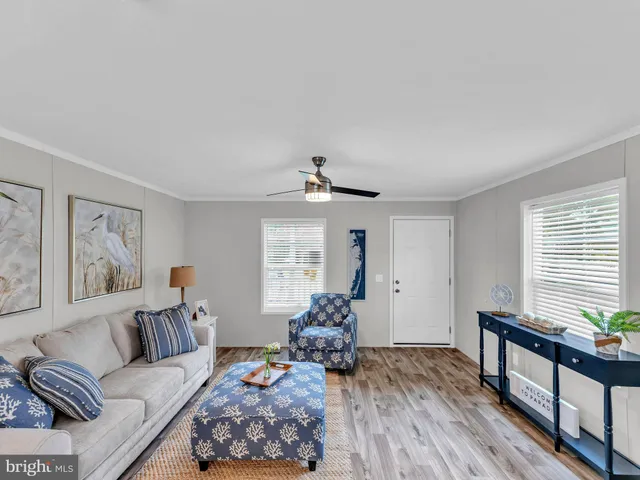 a living room with furniture two window and a wooden floor