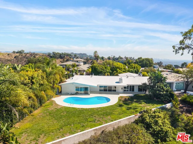 a view of swimming pool with a table and chairs under an umbrella
