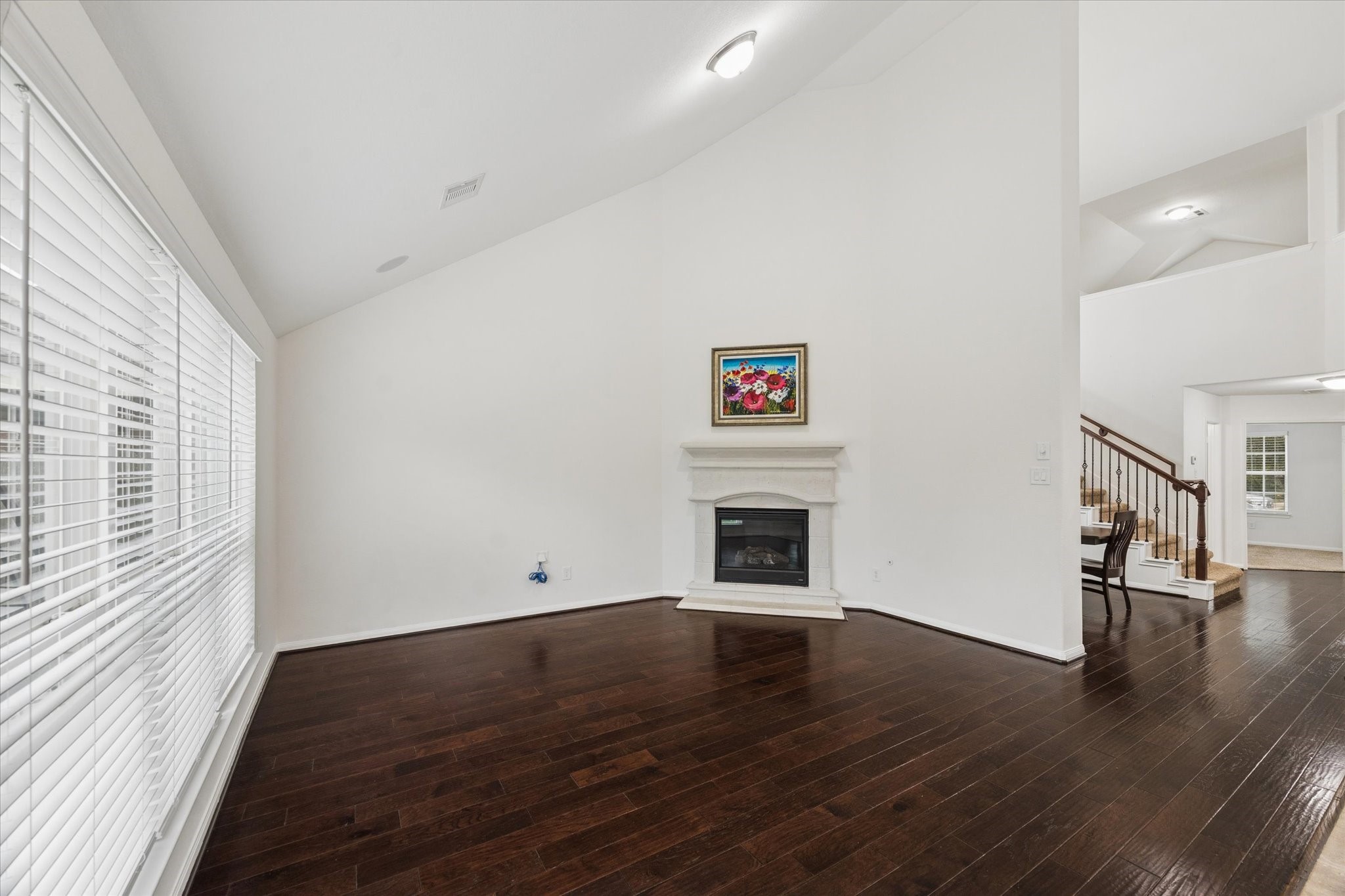 7015 Riata Hills Lane Spring, TX 77379 - Photo 8 of 33 The living room showcases soaring ceilings and a striking fireplace as its focal point, creating a warm and inviting atmosphere. Designed for both comfort and entertaining, the space offers an ideal wall for a large television and is filled with natural light from expansive windows.