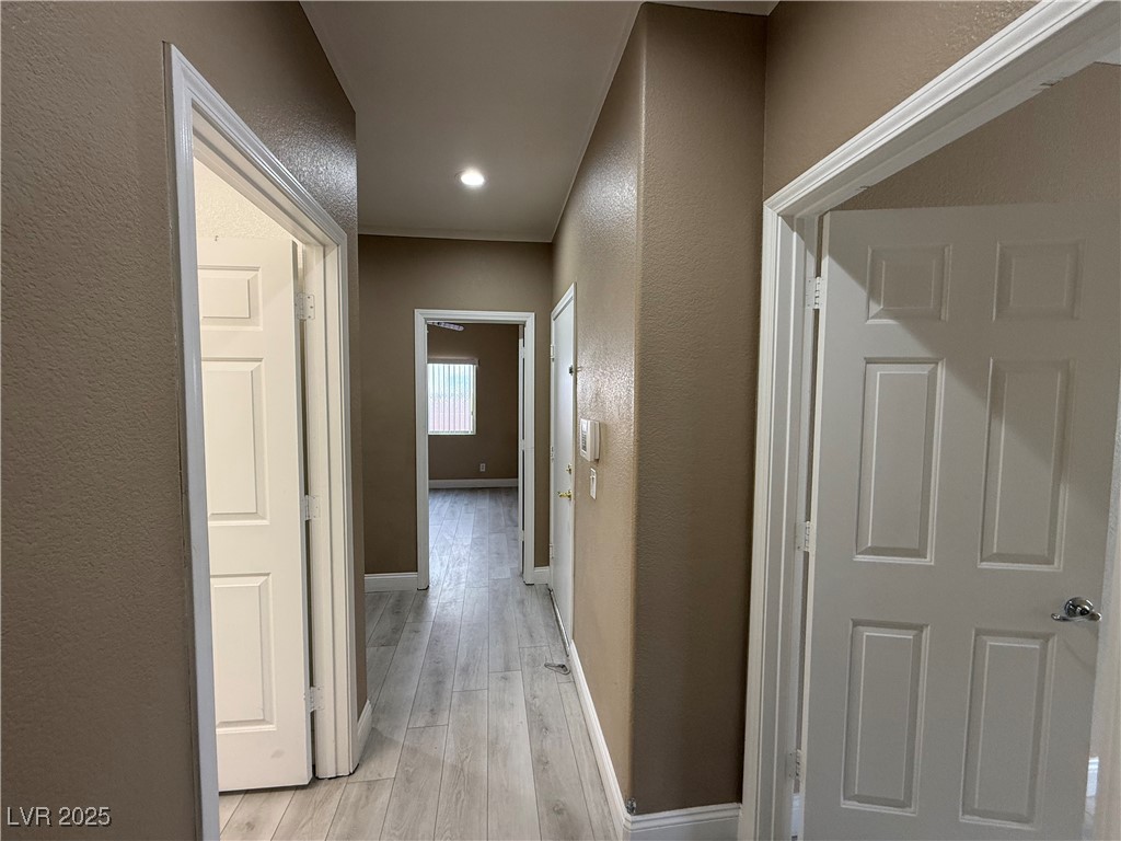 7062 Russell Ranch Avenue Las Vegas, NV 89113 - Photo 21 of 32 Hallway featuring baseboards, light wood-type flooring, and a textured wall