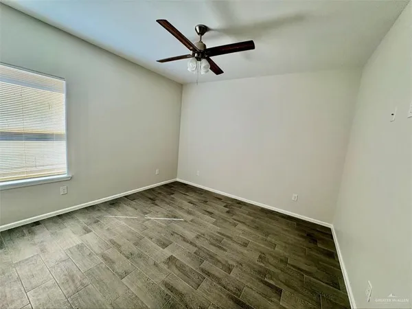 a view of empty room with wooden floor and ceiling fan