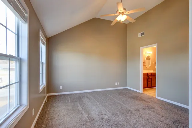 an empty room with windows and fan