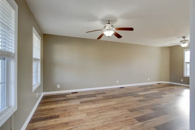 a view of empty room with wooden floor and fan