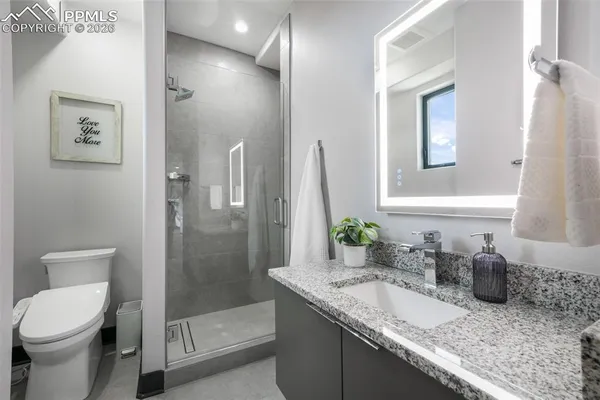 a bathroom with a granite countertop sink a toilet and shower