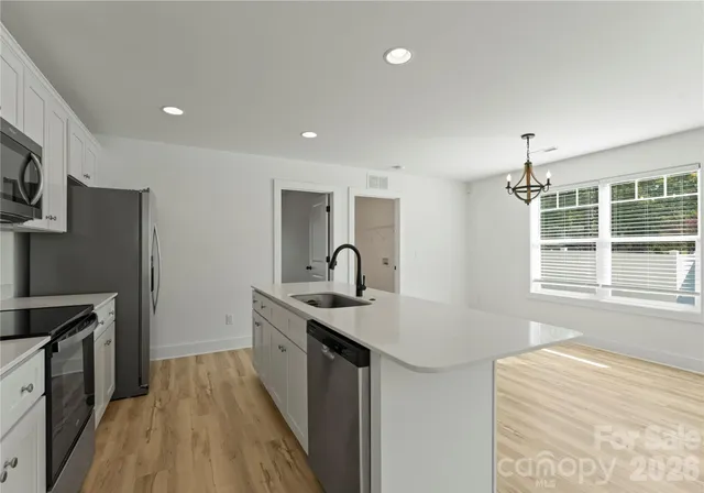a kitchen with stainless steel appliances granite countertop a sink and dishwasher a stove top oven with wooden floor