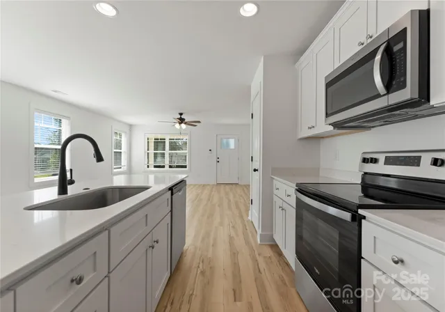 a kitchen with stainless steel appliances granite countertop a sink and dishwasher a stove top oven with wooden floor