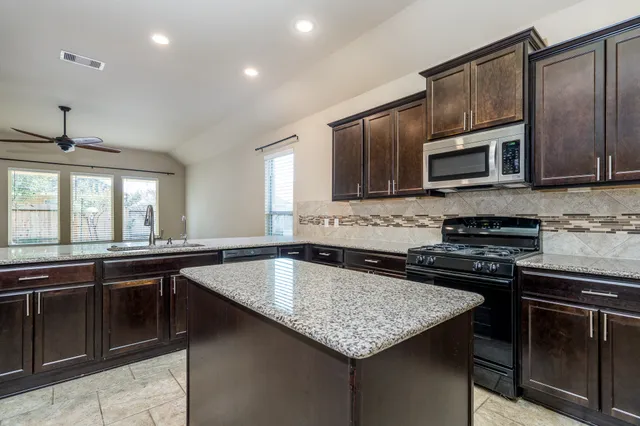 a kitchen with stainless steel appliances a stove sink microwave and cabinets