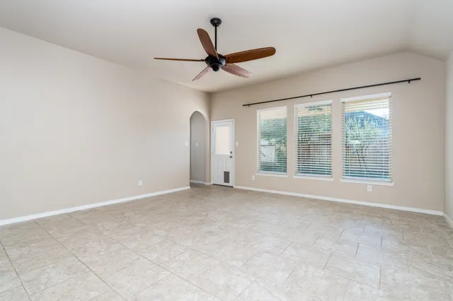an empty room with a ceiling fan and window
