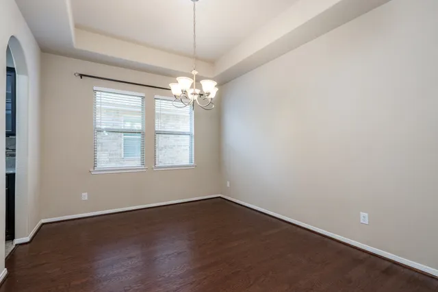 an empty room with wooden floor chandelier and window