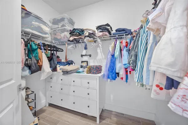 a view of walk in closet with clothes and shoes