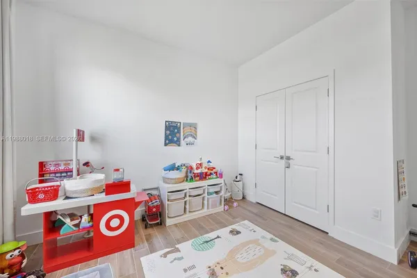 a utility room with fridge and wooden floor