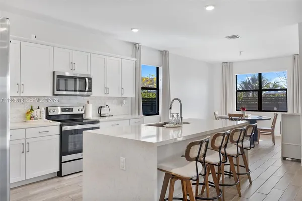 a kitchen with stainless steel appliances granite countertop a stove top oven a sink a dining table and chairs