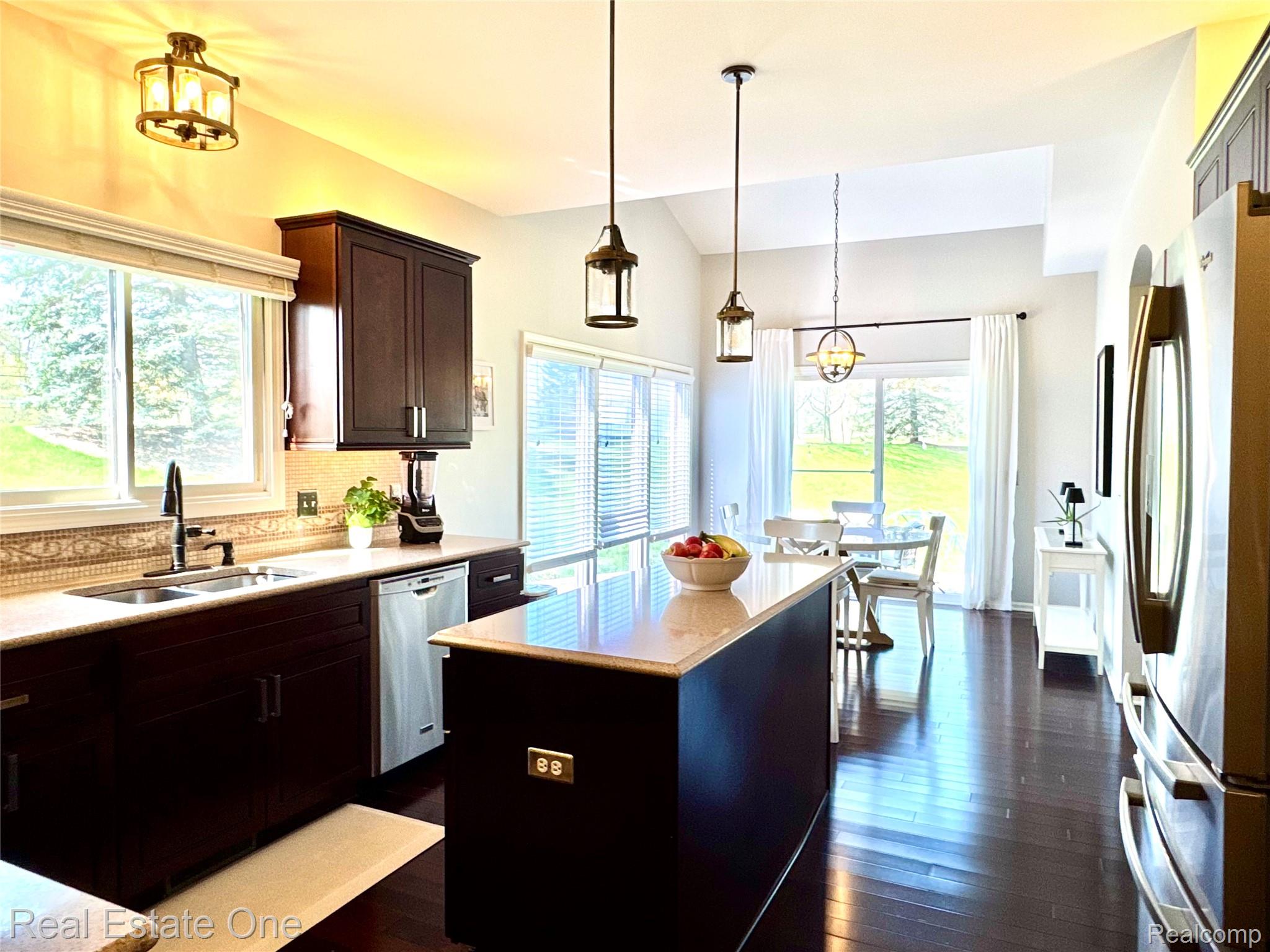 419 Roundview Drive Rochester, MI 48307 - Photo 11 of 29 Kitchen with stainless steel appliances, a kitchen island, dark wood-style flooring, dark wood finish cabinetry, and lofted ceiling