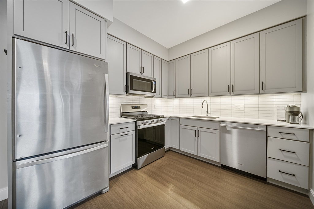 11 Walley Street, Unit 202 Boston, MA 02128 - Photo 5 of 24 a kitchen with white cabinets stainless steel appliances and a refrigerator