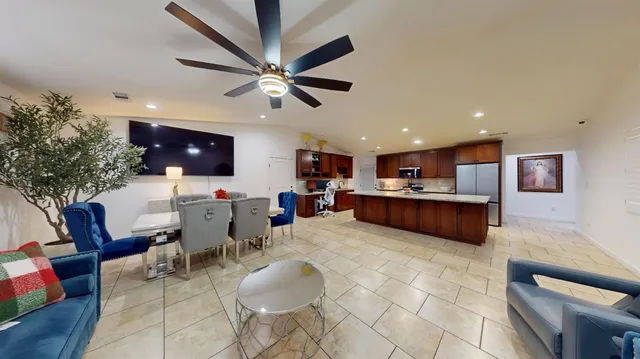 a living room with stainless steel appliances furniture a rug and a kitchen view