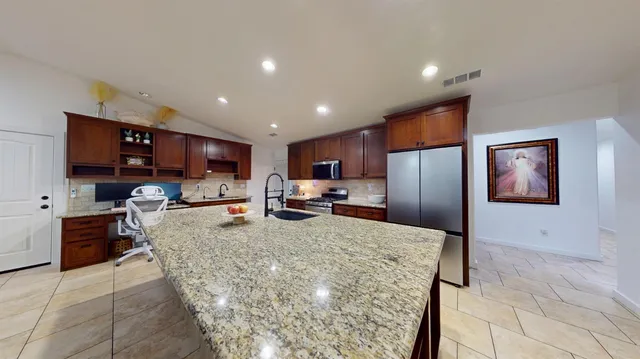 a large kitchen with kitchen island granite countertop a large counter top stainless steel appliances and cabinets
