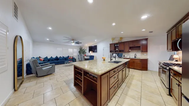 a kitchen with stainless steel appliances granite countertop a stove top oven a sink dishwasher and a refrigerator