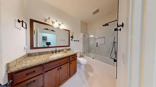 a bathroom with a granite countertop double vanity sink mirror and shower
