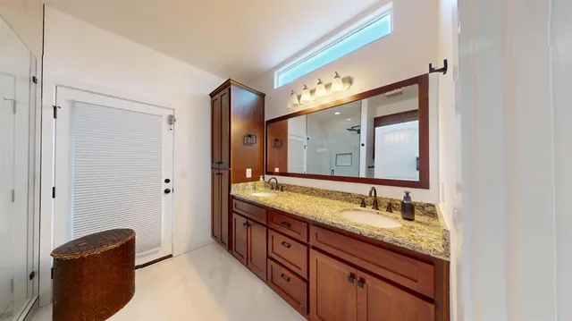 a bathroom with a granite countertop double vanity sink and a mirror