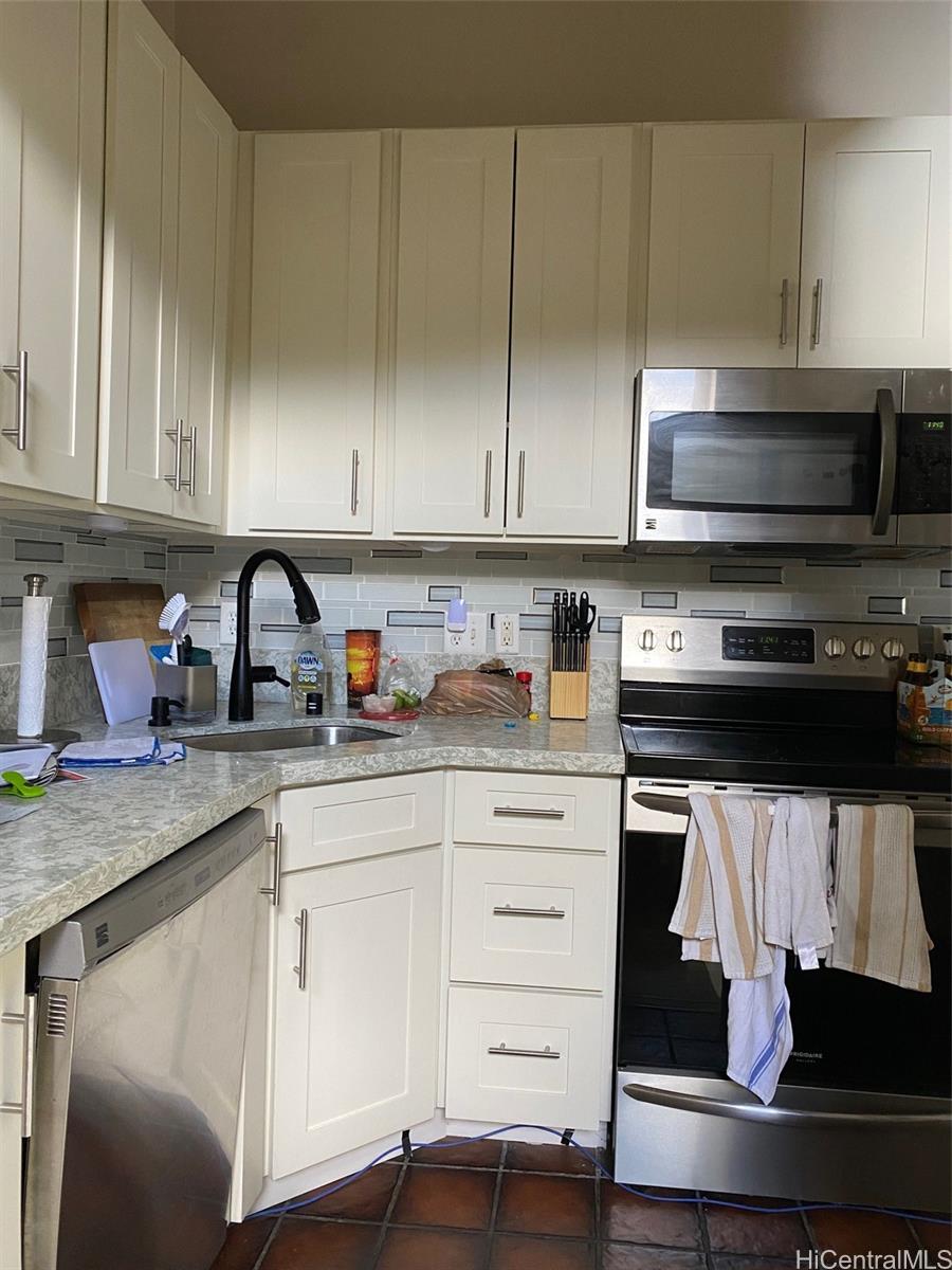 45-315 Lilipuna Road, Unit A306 Kaneohe, HI 96744 - Photo 6 of 19 a kitchen with stainless steel appliances granite countertop a stove a sink and white cabinets