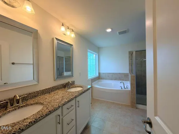 a bathroom with a granite countertop tub a sink and a mirror