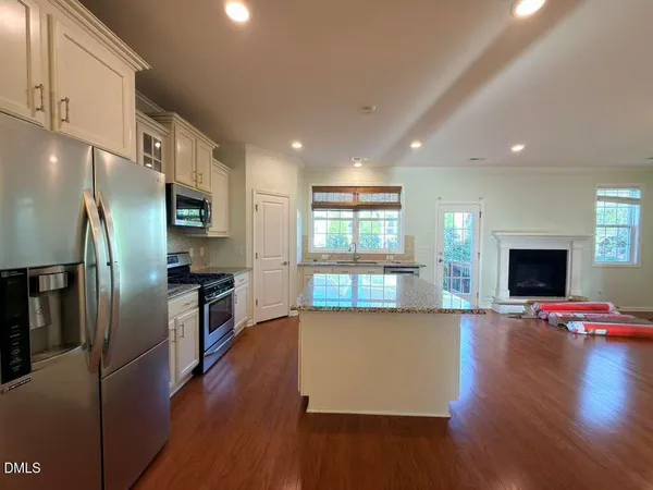 a kitchen with stainless steel appliances a refrigerator a stove top oven a sink dishwasher and a oven with wooden floor