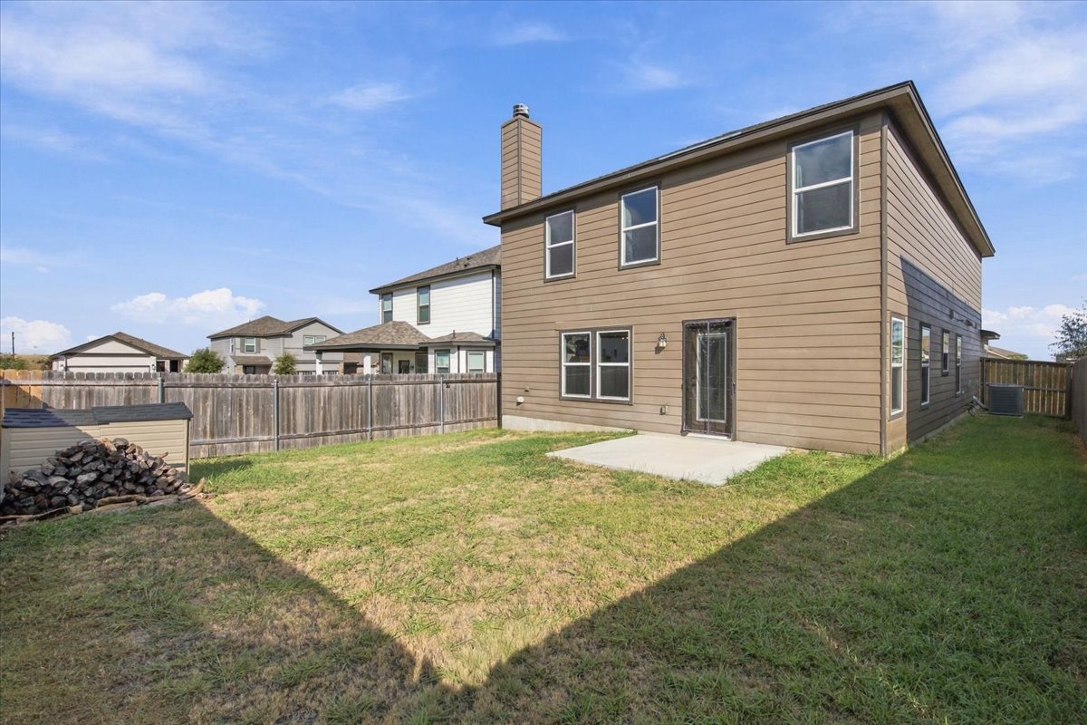 104 Rooster Way Jarrell, TX 76537 - Photo 28 of 33 A spacious grassy yard features a concrete patio and full wood fencing.