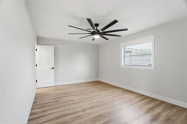 a view of an empty room with wooden floor and a window