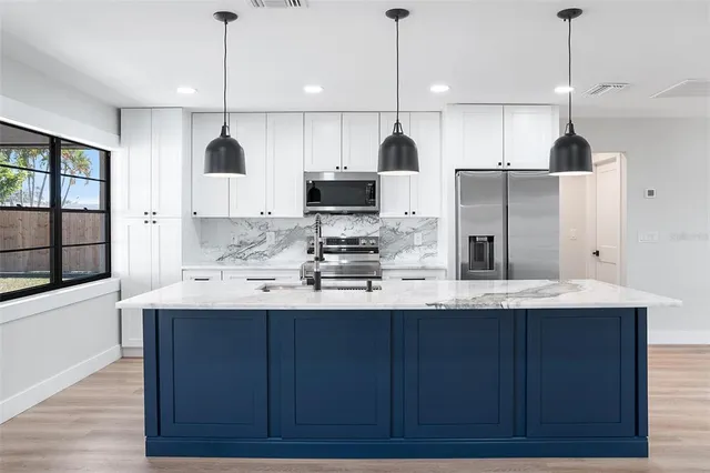 a kitchen with stainless steel appliances granite countertop a sink a refrigerator and a stove