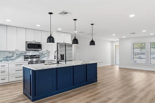 a kitchen with stainless steel appliances granite countertop a sink a stove and a wooden floors