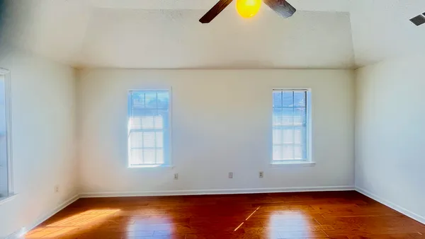 an empty room with wooden floor and windows