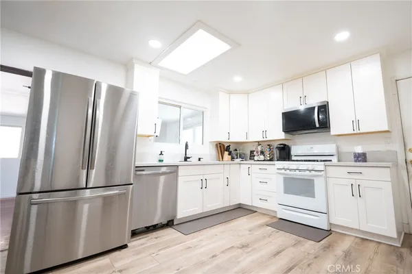 a kitchen with stainless steel appliances a refrigerator a stove top oven a sink and cabinets