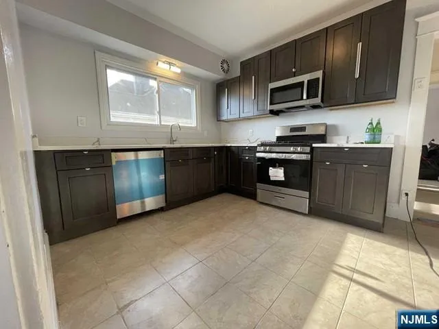 a kitchen with stainless steel appliances granite countertop a stove top oven a sink dishwasher and a microwave oven on the blue kitchen countertops