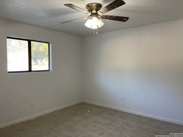 an empty room with windows and fan