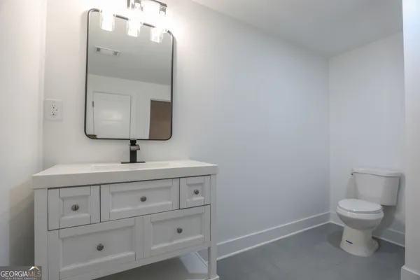 a bathroom with a toilet sink vanity and mirror