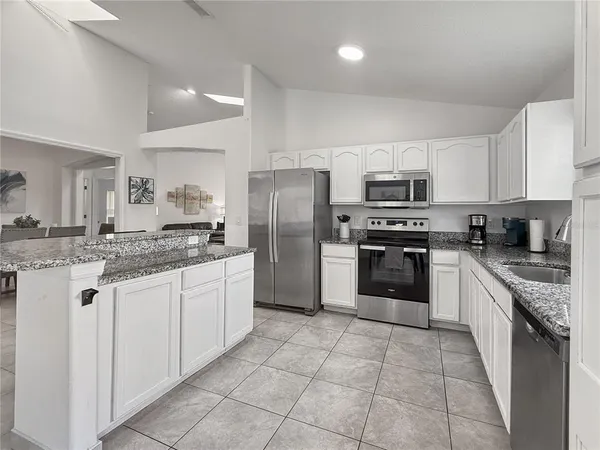 a large kitchen with stainless steel appliances granite countertop a stove top oven a sink and a refrigerator