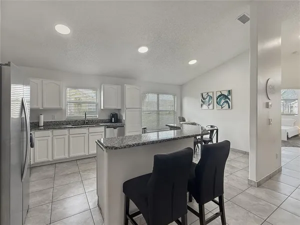 a kitchen with a dining table chairs cabinets and stainless steel appliances