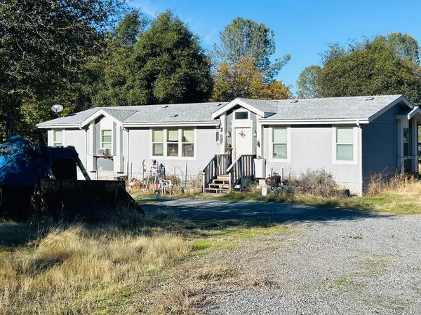 a front view of a house with a garden and lake view