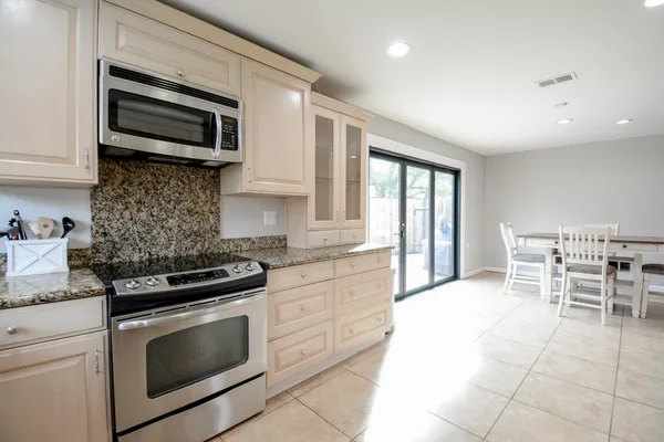 a kitchen with granite countertop a stove top oven microwave and cabinets