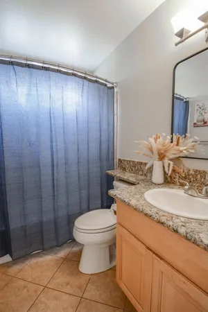 a bathroom with a granite countertop toilet and a sink