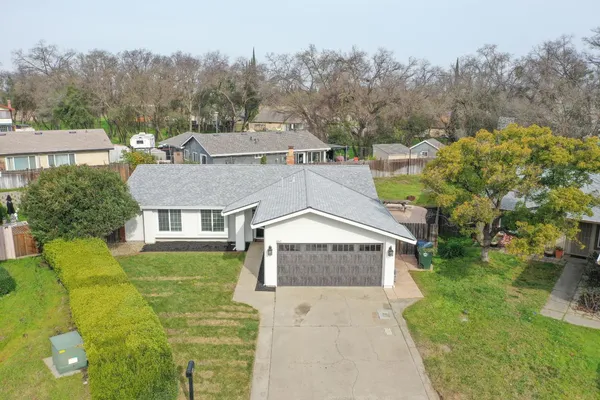 a aerial view of a house next to a big yard and large trees