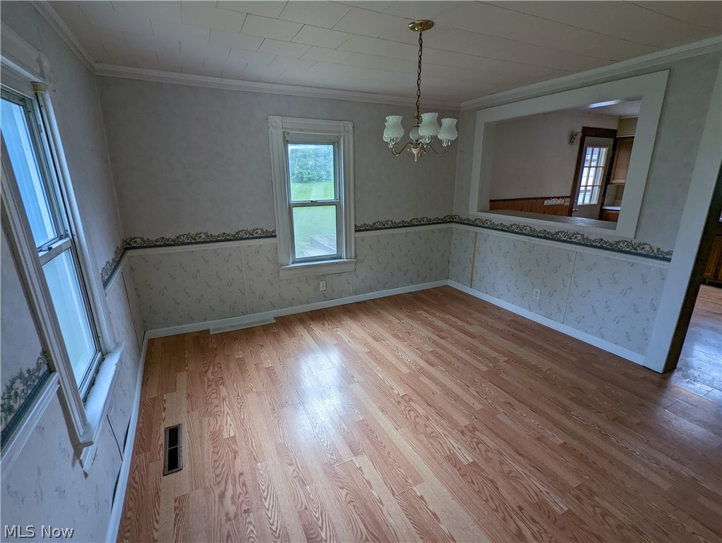 308 Thomas Road Lisbon, OH 44432 - Photo 5 of 13 Empty room featuring crown molding, hardwood / wood-style flooring, and an inviting chandelier
