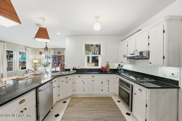 a kitchen with stainless steel appliances kitchen island granite countertop a table chairs and a refrigerator