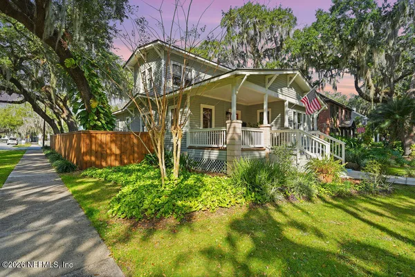a view of a house with a small yard plants and large trees