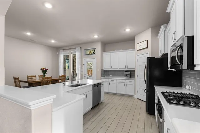 a kitchen with white cabinets and appliances