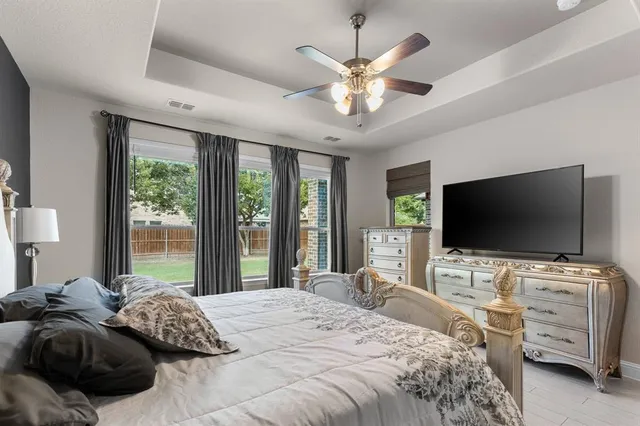 a bedroom with a bed and a flat tv screen on dresser