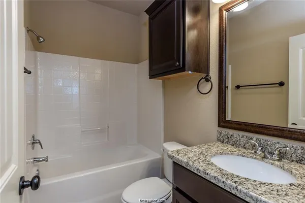 a bathroom with a granite countertop sink toilet and shower