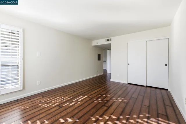 a view of an empty room with wooden floor and a window