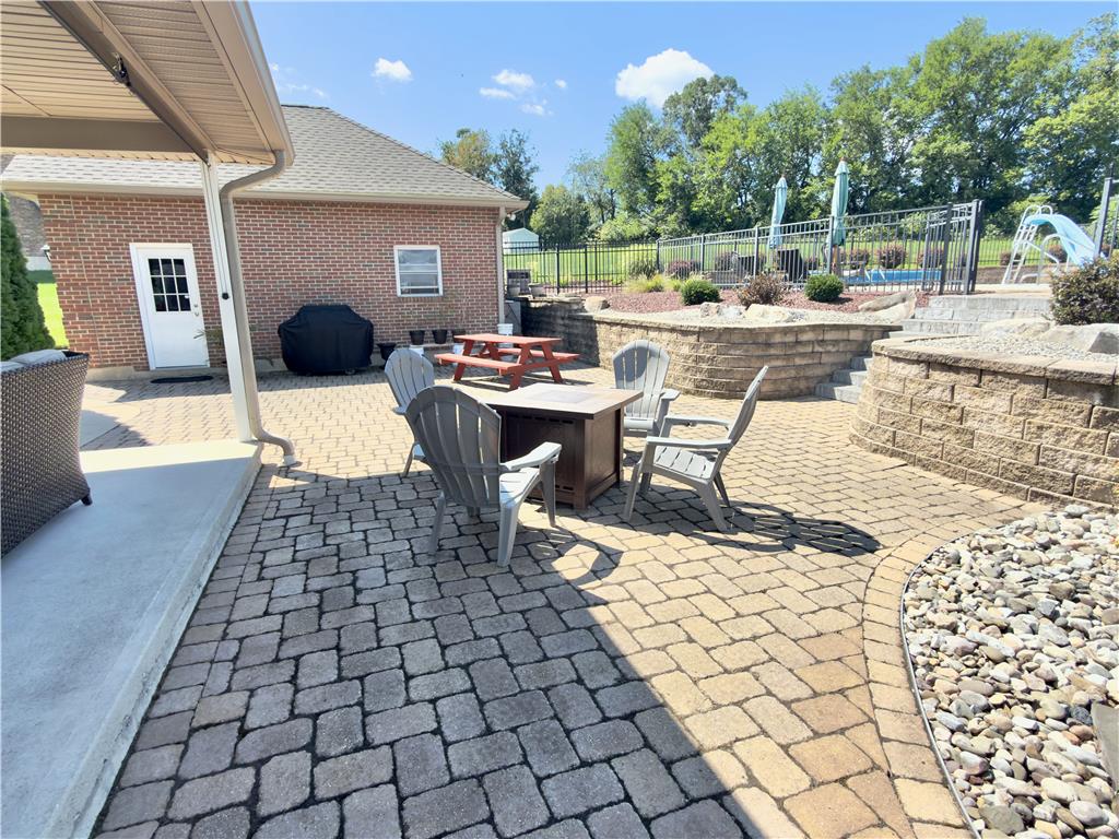 4982 Abbey Road Coplay, PA 18037 - Photo 49 of 55 An expansive paver patio sits adjacent to the brick home with tiered stone retaining walls.