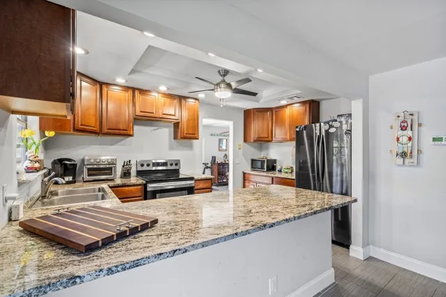 a kitchen with stainless steel appliances granite countertop a sink a stove and a refrigerator